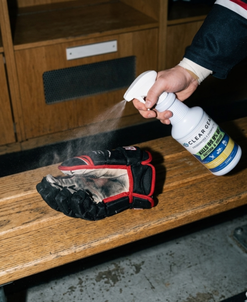 spraying Clear Gear disinfectant onto hockey gear